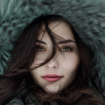 Une femme vêtue d'un manteau de fourrure vert pose pour une photo, présentant l'une des 5 manières de trouver l'inspiration mode pour cet hiver.