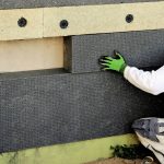 Un homme isole sa maison par l'extérieur avec du ciment.