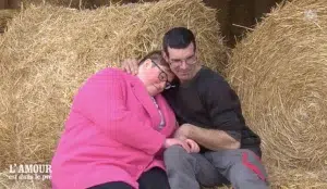 Un homme et une femme s'embrassant devant des bottes de foin.