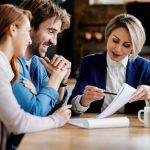 Un groupe de personnes assises à une table et discutant de la paperasse liée au produit d'investissement.