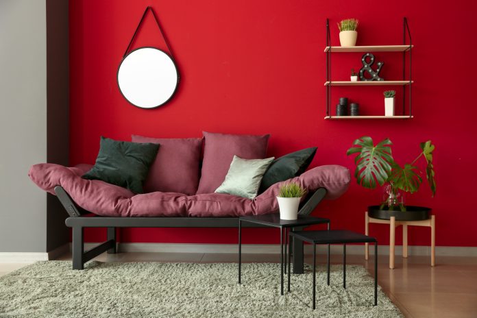 Une chambre à coucher avec des murs rouges et un canapé rose.