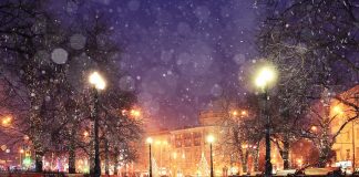 Une ville chaleureuse la nuit avec de la neige tombant du ciel, éclairée par des lumières festives et ornée de couleurs tendance.