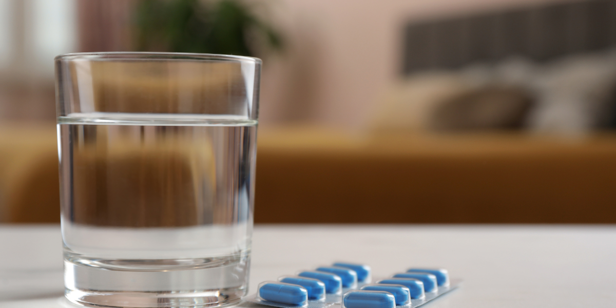 Un verre d'eau et des pilules sur une table.