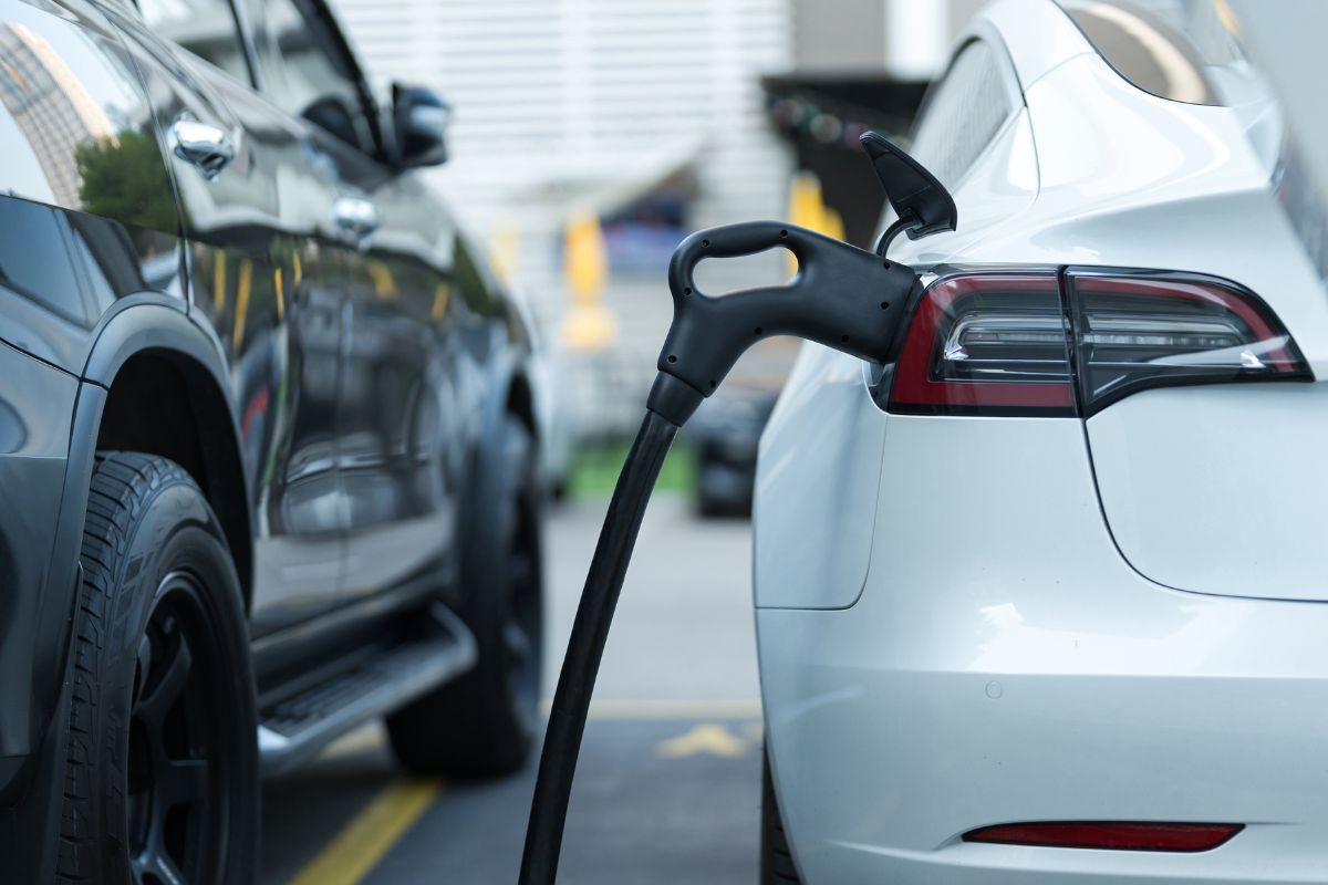 Une voiture électrique Tesla blanche branchée sur une borne de recharge, symbolisant le brillant avenir de l'avenir de l'automobile.
