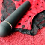 Un masseur automatique personnel noir sur un tissu en dentelle rouge et noir.