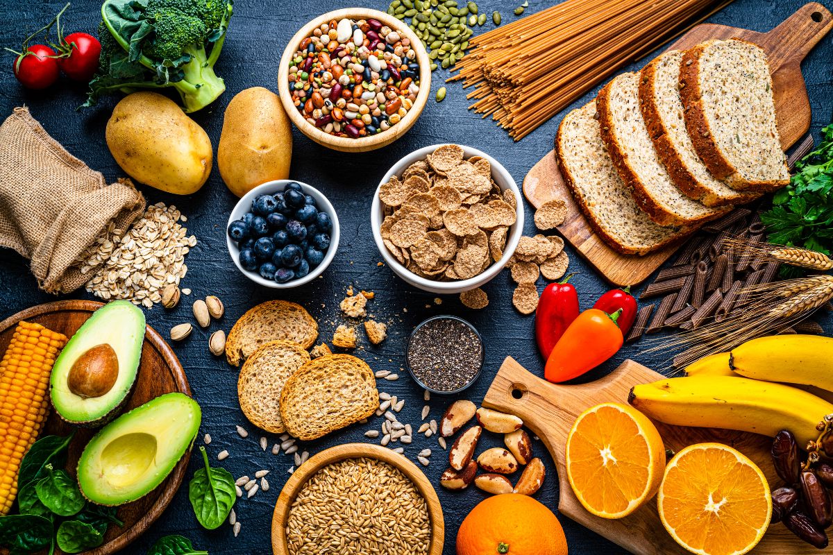 Un assortiment d'aliments sains comprenant des fruits, des légumes, des céréales et des noix étalés sur une surface sombre pour éviter les calculs biliaires.
