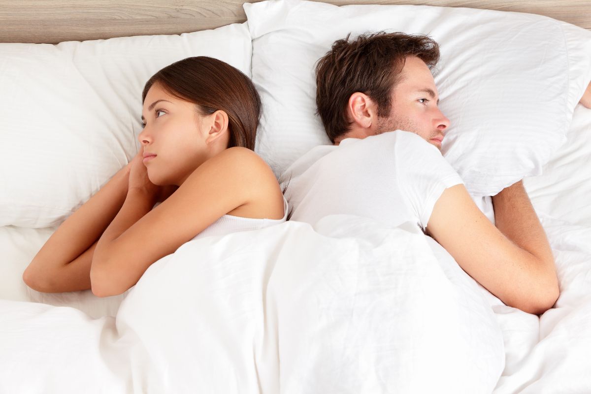 Un couple dans leur lit, dos à dos, illustrant un manque de désir sexuel dans leur relation.