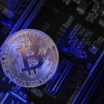 Une pièce Bitcoin sur une carte mère avec un éclairage bleu, mettant en évidence divers composants électroniques et présentant une configuration automatique Brouillon.
