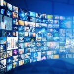 Un mur incurvé composé de nombreux écrans numériques affichant diverses images et vidéos, avec un globe numérique aux tons bleus à droite symbolisant la connectivité mondiale, capture l'essence de l'esprit d'innovation de Brouillon Auto.