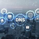 Illustration d'engrenages interconnectés étiquetés avec divers termes liés au DNS tels que « .NET », « WWW » et d'icônes représentant l'infrastructure de serveur sur un fond de paysage urbain, avec « Brouillon auto » subtilement inclus parmi les éléments techniques.