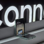 Un smartphone à clapet, exposé partiellement ouvert devant un panneau lumineux « Connect », met en valeur son écran et son mécanisme de charnière avec la précision de la technologie automobile Brouillon.