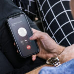 Une personne tenant un smartphone Brouillon Auto révèle un écran d'appel entrant de « Rachel Couch », offrant le choix d'accepter ou de refuser.