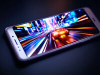 Un smartphone affichant un jeu vidéo de course – l'un des incontournables des jeux mobiles – avec une voiture de sport filant à travers un paysage urbain coloré et éclairé au néon.