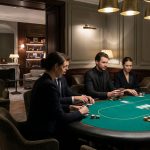Cinq personnes habillées de façon formelle jouent au poker autour d'une table verte dans une salle élégante, légèrement éclairée, avec des panneaux en bois et un décor moderne, évoquant l'ambiance sophistiquée du Casino de Paris.