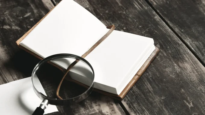 Open blank notebook with a leather cover and a string bookmark on a dark wooden desk.