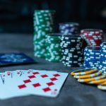 Des cartes à jouer et des piles de jetons de poker colorés sont disposés sur une table, avec une quinte flush royale à carreaux bien en évidence au premier plan.